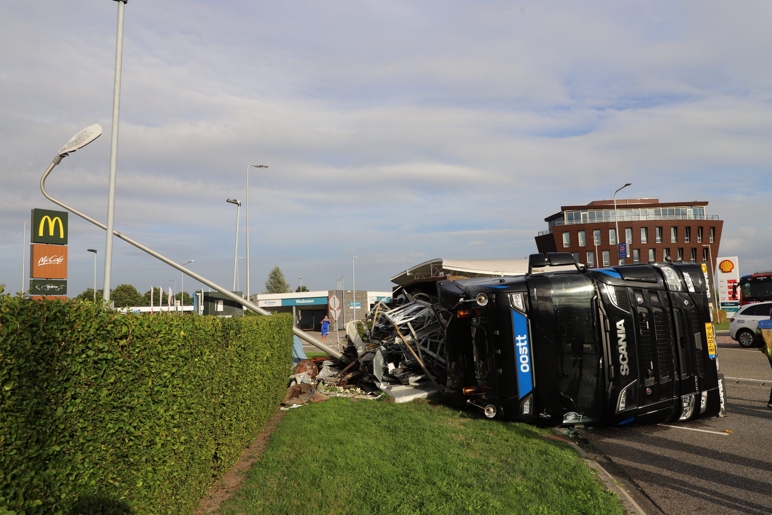 Vrachtwagen met schroot kantelt op rotonde